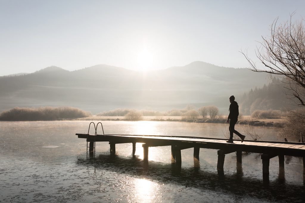 A man walking down a pier at Lake Podpeč, Slovenia.